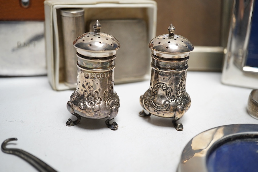 A collection of white metal and hallmarked silver to include three photo frames, a mounted glass flask, a compact, a lipstick holder, a cased pair of Victorian pepper pots, two pairs of Georgian sugar tongs and a mounted